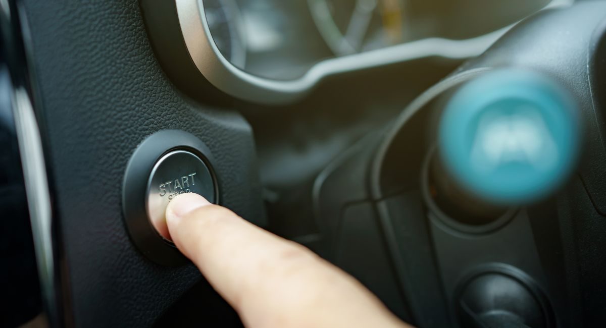 A person clicking on the Start button in the car to start the car battery